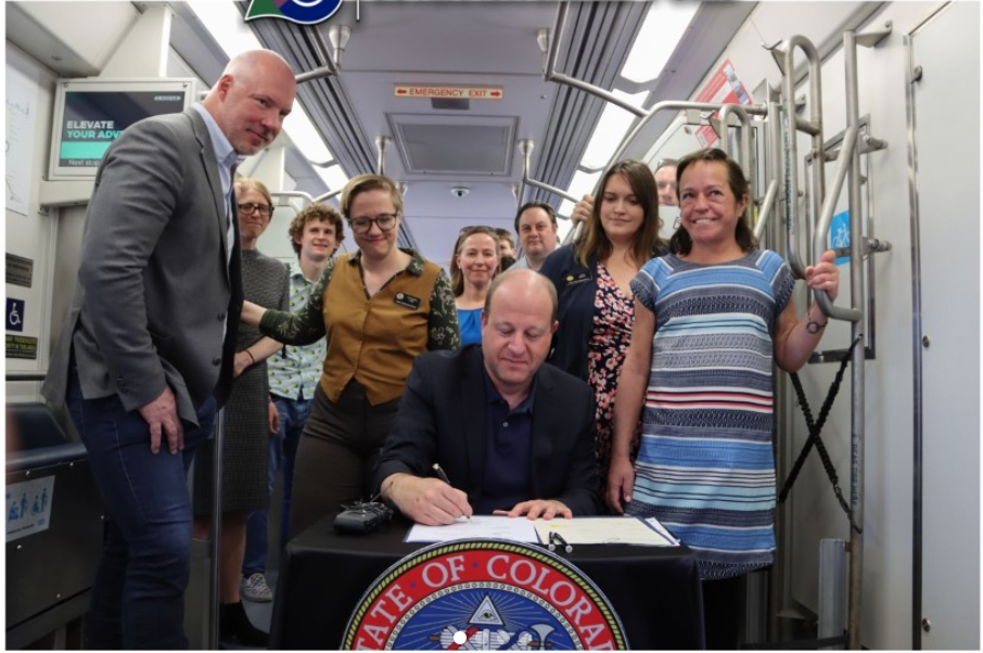 Colorado Governor Polis signs transportation bill on the train.